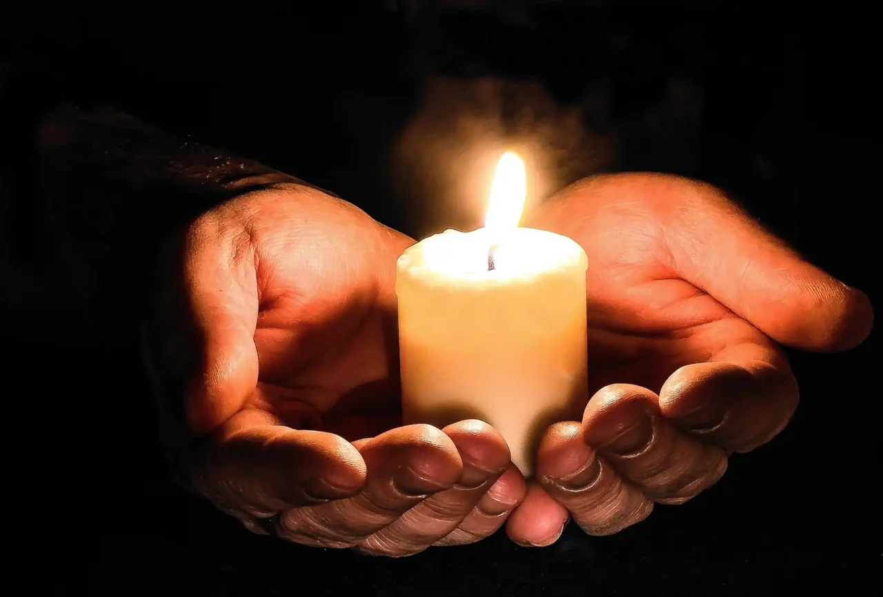 Ręce trzymające zapaloną świecę